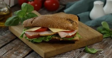 Lezzetli ekmekli sandviçi ahşap masaya koyan kadın, yakın plan.