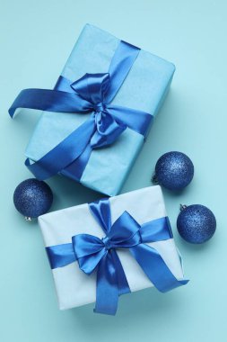 Noel baloları ve hediye kutuları açık mavi arka planda, düz yatıyordu