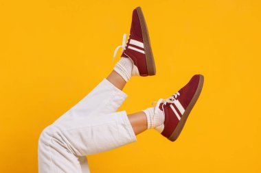 Sarı arka planda şık bordo ayakkabılar giyen kadın, yakın plan.