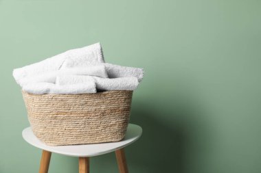 İçerideki yeşil duvarın yanındaki masada havluları olan çamaşır sepeti. Metin için boşluk