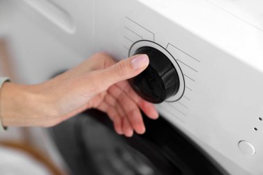 Çamaşır makinesi programını seçen kadın, yakın plan.