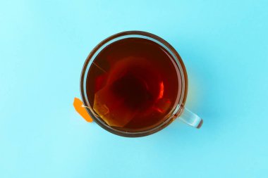 Çay demleniyor. Açık mavi arkaplanda çay poşeti, üst manzara.