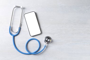 Sağlığınıza. Akıllı telefon ve steteskop açık dokulu masa, düz yatak. Metin için boşluk