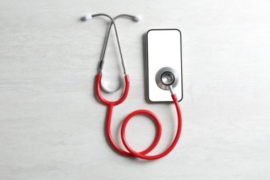 Sağlığınıza. Akıllı telefon ve steteskop açık dokulu masa, düz yatış