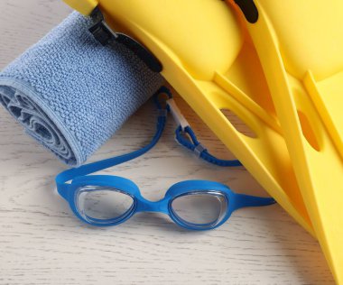 Sarı paletler, koruyucu gözlükler ve açık tahta masa üzerine havlu, düz yatış. Yüzme aksesuarı