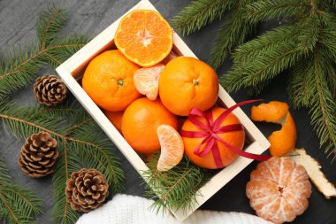 Sandıkta mandalinalar, siyah masada köknar dalları ve koniler, düz yatıyordu.