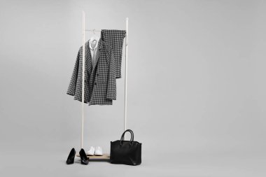 Açık gri arkaplanda asılı farklı kıyafetler, çanta ve ayakkabılar, metin için boşluk