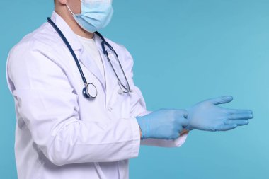 Doktor açık mavi arka plana eldiven takıyor, yakın plan. Metin için boşluk