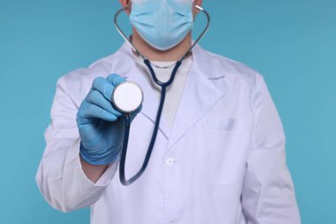 Açık mavi arka planda steteskobu olan doktor, seçici odak