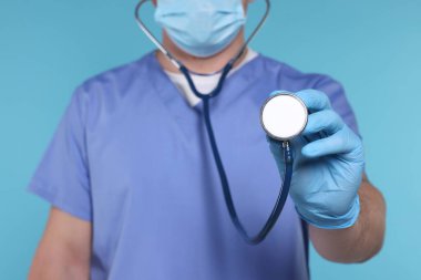 Açık mavi arka planda steteskobu olan doktor, seçici odak