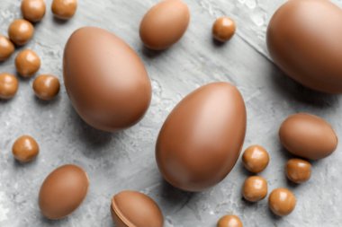 Paskalya kutlaması. Gri desenli masa üzerinde bir sürü çikolatalı yumurta ve kuru üzüm.