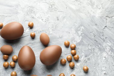 Paskalya kutlaması. Gri desenli masa üzerinde bir sürü çikolata yumurtası ve dragee, metin için boşluk ile düz yatıyordu.