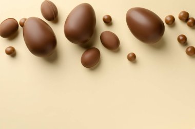 Paskalya kutlaması. Sarı arka planda bir sürü çikolata yumurtası ve sürükleyici var, düz bir zeminde metin için yer var.