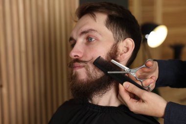 Berber dükkanında adamın sakalını buduyor, yakın plan.