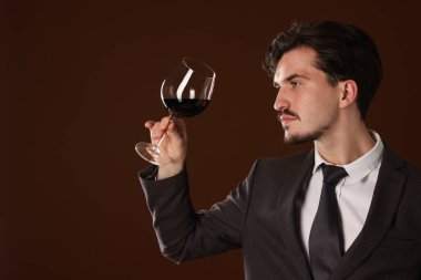 Kahverengi arka planda kırmızı şarap kadehi olan profesyonel şarap garsonu. Metin için boşluk