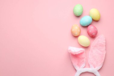 Mutlu Paskalyalar. Tavşan kulaklı şirin saç bandı ve pembe arka planda yumurta boyası, düz yatak. Metin için boşluk