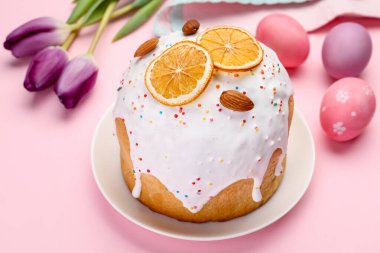 Güzel Paskalya pastası, pembe arka planda yumurtalar ve laleler, yakın plan.