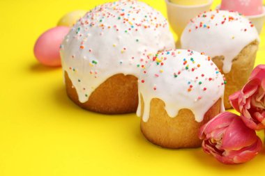 Lezzetli Paskalya pastaları, yumurta ve laleler sarı arka planda, yakın plan.