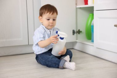 Evde çocuk güvenliği. Küçük çocuk mutfakta temizlik ürünleriyle dolap açıyor.