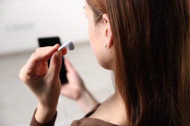 Kulaklığı içeride olan akıllı telefonu tutan kadın, yakın plan.