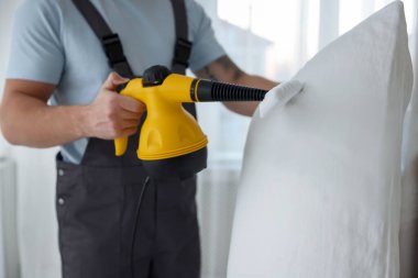 Haşere kontrol görevlisi yastığı temizliyor, kapalı alanda temizliyor, yakın plan.