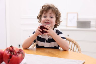 Küçük çocuk içeride taze nar suyu içiyor.