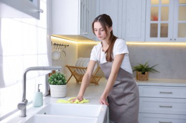 Mutfakta mikrofiber bezle tezgahı silen kadın.