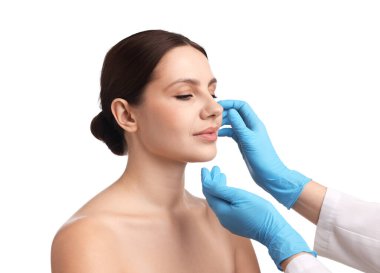 Doktor, estetik ameliyattan önce beyaz arka planda hastanın yüzünü kontrol ediyor.