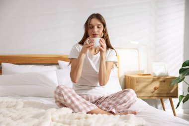 Evdeki yatakta bir fincan aromatik kahveyle güzel bir kadın.