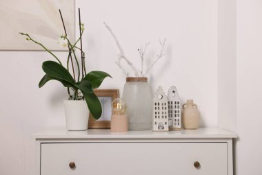 Beyaz duvarın yanındaki dolapta güzel vazolar ve diğer dekorlar var.