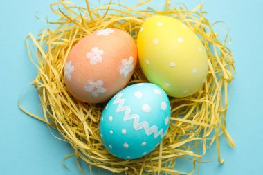 Birçok boyanmış Paskalya yumurtası ve saman açık mavi arka planda, üst manzara