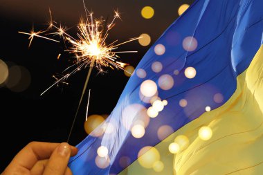 Ulusal bayrak taşıyan Ukrayna bayramı tebrik kartı tasarımı. Siyah arkaplanda yanan maytap ve bokeh ışıkları