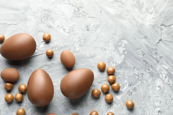 Paskalya kutlaması. Gri desenli masa üzerinde bir sürü çikolata yumurtası ve dragee, metin için boşluk ile düz yatıyordu.