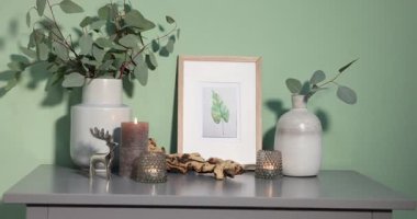 Okaliptüslü güzel vazolar ve zeytin duvarının yanındaki gri masada diğer dekorlar.