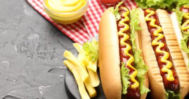 Ketçaplı sosisli sandviç, hardal, marul ve patates kızartması, yakın plan. Kamera sağa hareket ediyor