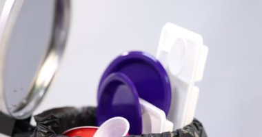 Açık gri arka planda plastik ambalajı çöp kutusuna atan kadın, yakın plan