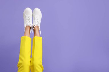 Violet 'in arka planında şık beyaz ayakkabılar giyen bir kadın, yakın plan. Metin için boşluk