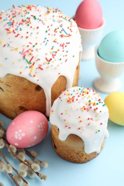 Lezzetli Paskalya pastaları, süslenmiş yumurtalar ve açık mavi arka planda söğüt dalları, yakın plan.