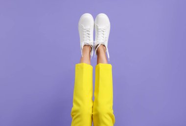 Mor arka planda şık beyaz ayakkabılar giyen kadın, yakın plan.