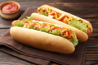 Ahşap masada soslu ve marullu lezzetli sosisliler, yakın plan.