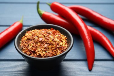 Kırmızı biber ve tanecikler mavi ahşap masada, yakın plan.