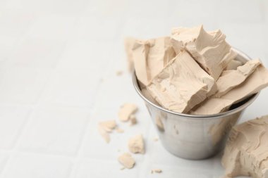 Tabaktaki taze maya parçaları beyaz fayanslı masada, yakın plan. Metin için boşluk