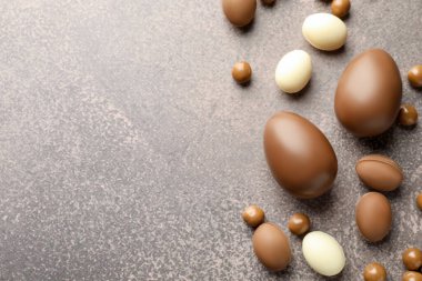 Paskalya kutlaması. Gri desenli masa üzerinde bir sürü çikolata yumurtası ve dragee, metin için boşluk ile düz yatıyordu.