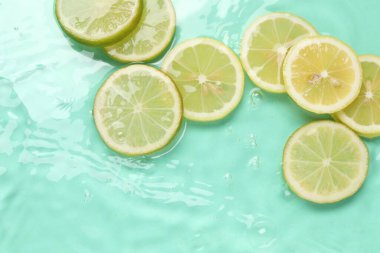 Turkuaz arka planda sudaki narenciye dilimleri, düzlük.