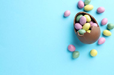 Paskalya kutlaması. Açık mavi arka planda şekerli kırık çikolata yumurtası, düz. Metin için boşluk