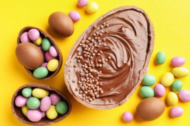 Sarı arka planda renkli şekerlemeli leziz çikolatalı yumurtalar. Mutlu Paskalyalar