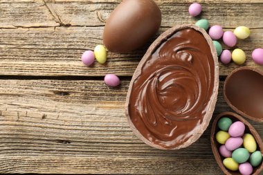 Mutlu Paskalyalar. Tahta masanın üzerinde renkli şekerlemeli leziz çikolatalı yumurtalar, düz yatak. Metin için boşluk