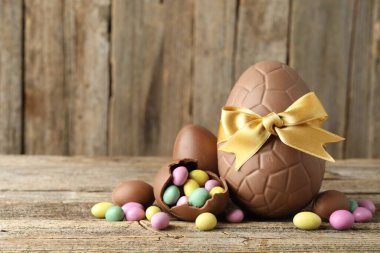 Mutlu Paskalyalar. Ahşap masada renkli şekerlemeli lezzetli çikolata yumurtaları, yakın plan. Metin için boşluk