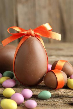 Ahşap masada renkli şekerlemeli lezzetli çikolata yumurtaları, yakın plan. Mutlu Paskalyalar