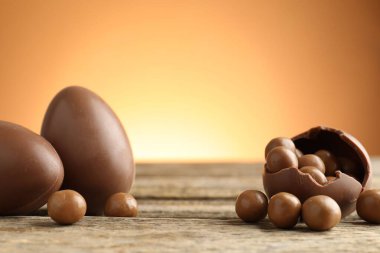 Ahşap masadaki çikolatalı yumurtalar, renkli arka plana karşı, yakın plan. Mutlu Paskalyalar